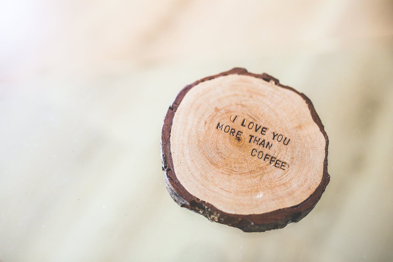 Rustic wooden coaster with the quote 'I love you more than coffee' engraved on it.